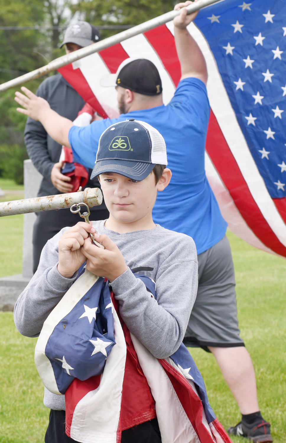 Caedyn Huston fastens a flag to a pole at Sharon Hill Cemetery in Kalona. He was there with sister, Adelyn, and his dad, Michael.